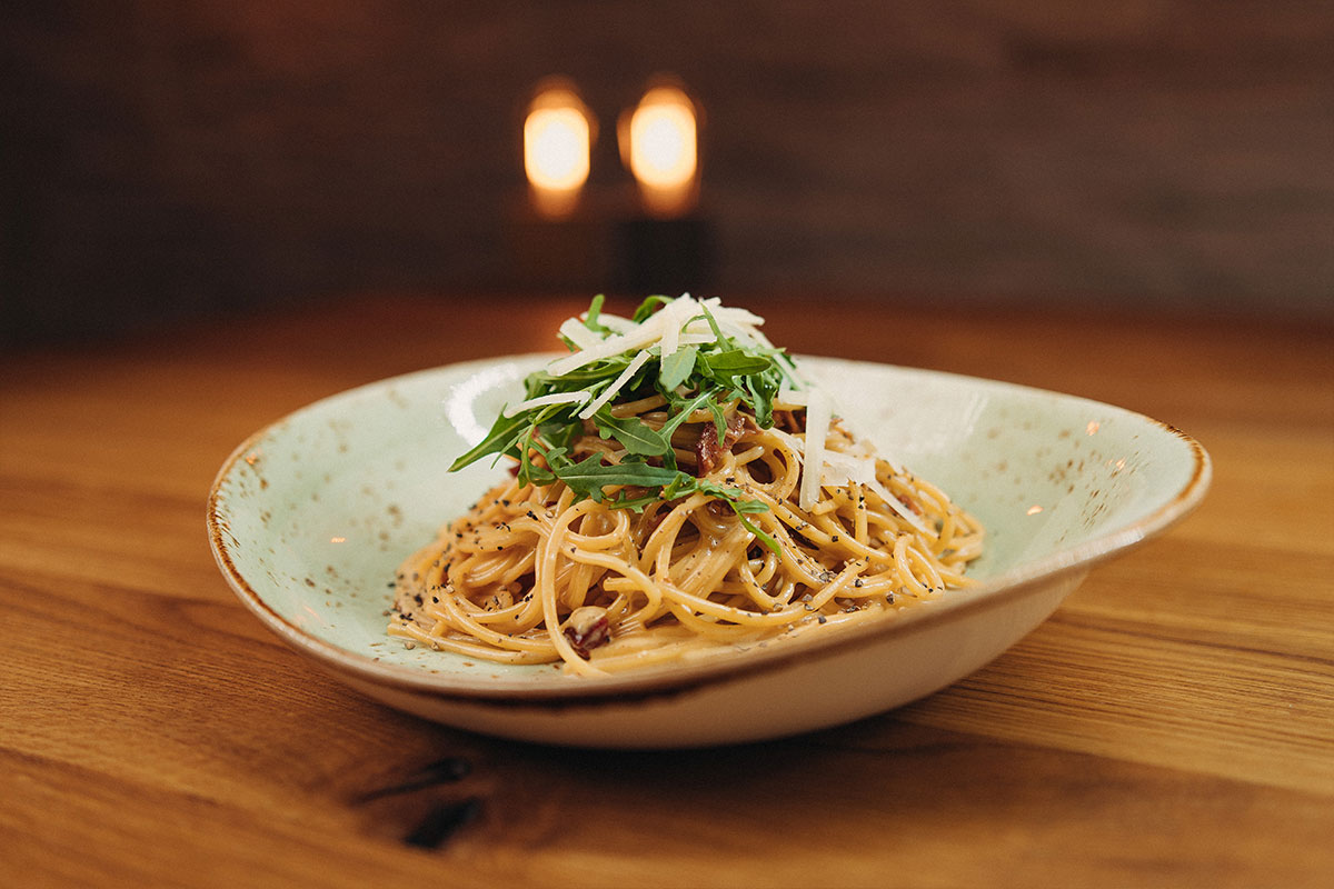 Spaghetti Carbonara mit feinen Schinkenwürfeln, in Ei-Sahnesauce, frischem Rucola und Parmegiano