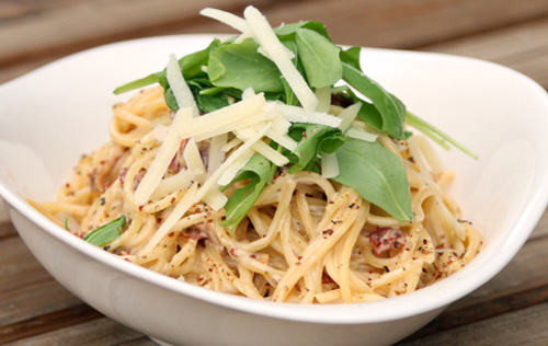 Spaghetti Carbonara mit feinen Schinkenwürfeln, in Ei-Sahnesauce, frischem Rucola und Parmegiano